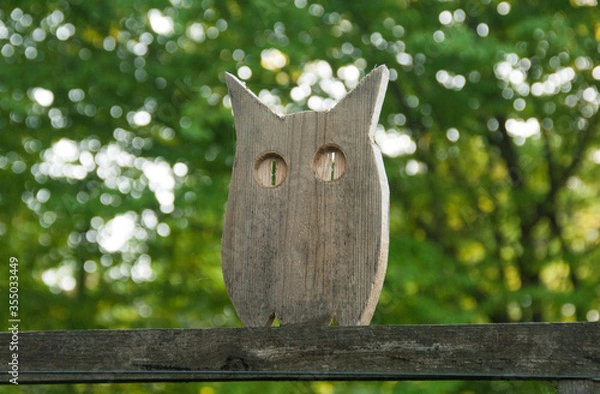 Fototapeta Handmade flat wooden figure of an owl in the garden. Woodwork, cutting tools. Creative wooden figure of an owl on a fence