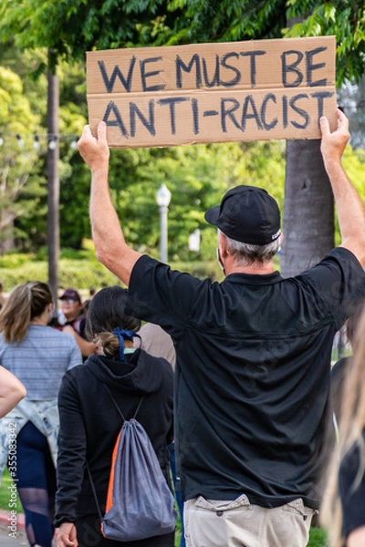 Obraz San Diego, California. June 1st, 2020. "We must be anti-racist" sign held by a middle age male at a pacific peaceful protest.
