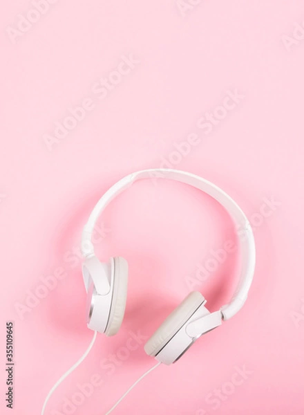 Fototapeta White headphones on pink background. Top view to the music. Around it is quiet, inside is loud. Respect for foreign borders.