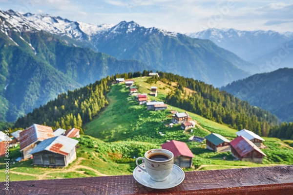 Fototapeta Drinking Turkish coffee and watching the traditional wooden houses of Pokut Plateau and snowy mountains. Landscape photo was taken at Rize, northeastern Karadeniz region of Turkey.