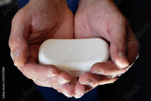 Fototapeta Man's hand holding a soap, man hands holding white antibacterial soap, self hygiene concept, covid-19 prevention