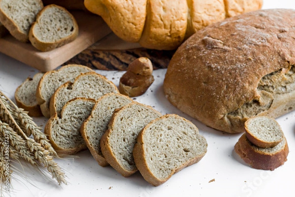 Fototapeta Sliced of whole wheat bread on wwhite with wheat ears.Close up taken