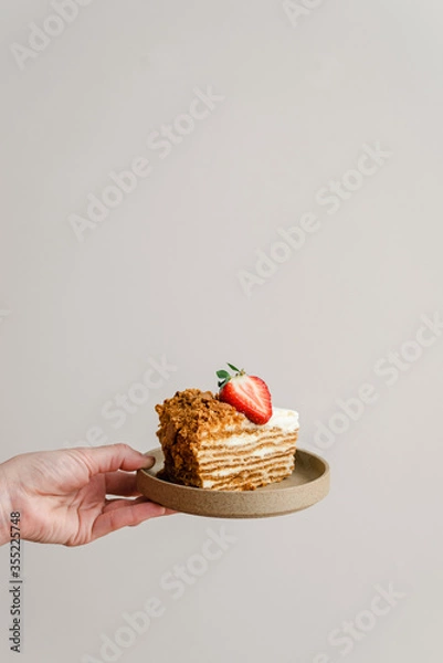 Fototapeta A piece of honey layered cake decorated with strawberries.