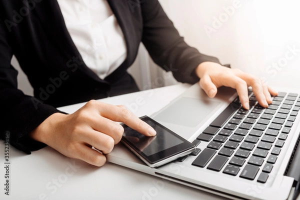 Fototapeta Businessman hands working with finances about cost and calculator and laptop with tablet, smartphone at office in morning light
