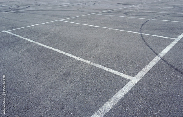 Fototapeta Asphalt texture with white line and tire marks.  Smooth asphalt road. Tarmac dark grey grainy road background.Top view