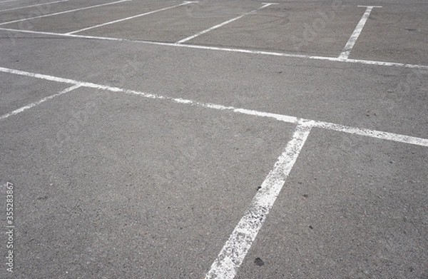 Fototapeta Dark asphalt road with marking lines. Tarmac texture. White disabled sign on a empty parking lot. Black tarmac texture with road marking 