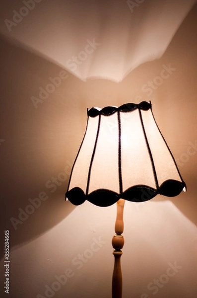 Fototapeta Table lamp with dramatic light pattern on wall