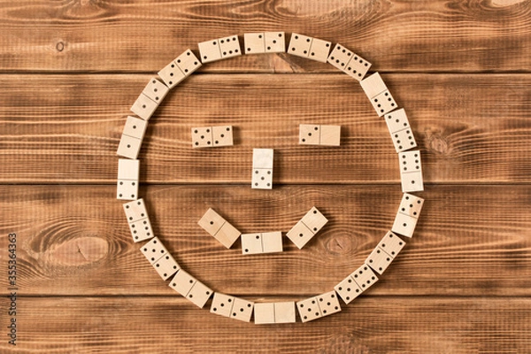 Fototapeta A game of dominoes. A smiley face made of Domino pieces on a wooden table.
