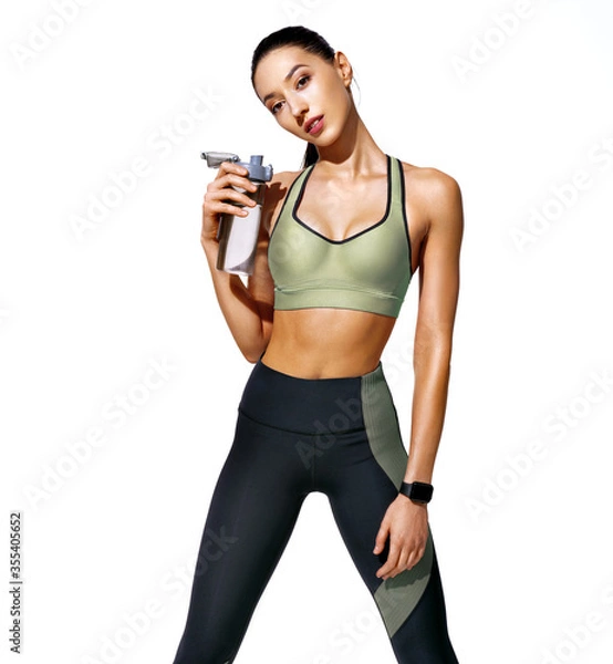 Fototapeta Resting time. Sweaty girl with opens bottle of water. Photo of girl with perfect body on white background. Strength and motivation