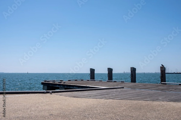 Fototapeta Empty Wooden Dock with Bollards Sea Scenery on a Bright Summer Day