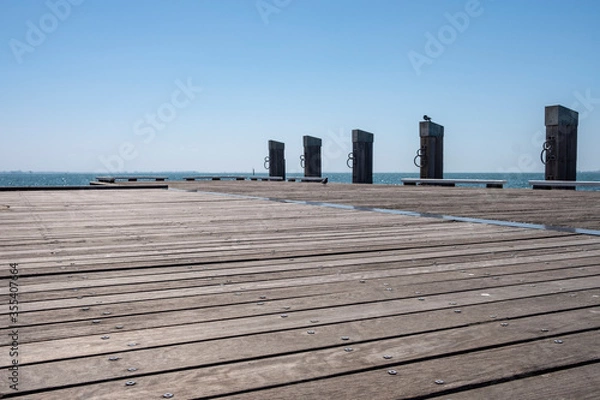 Fototapeta Empty Wooden Dock with Bollards Sea Scenery on a Bright Summer Day