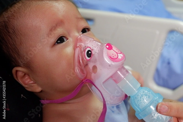Obraz Sick boy inhalation therapy by the mask of inhaler. Boy is sick with Respiratory Syncytial Virus. Patient Boy use inhalation with Nebulizer mask at hospital. The baby are spraying bronchodilators .