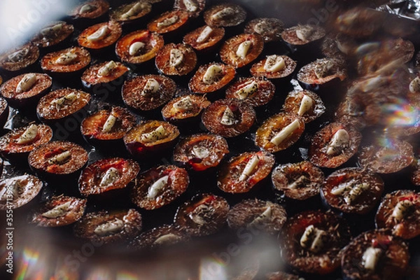 Fototapeta Dried plums with garlic. Plums on a baking sheet. Plums and garlic in the oven. Delicious dried plums.