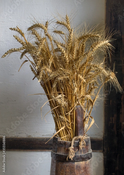 Fototapeta Wheat stalks placed in a wooden vessel in the village.