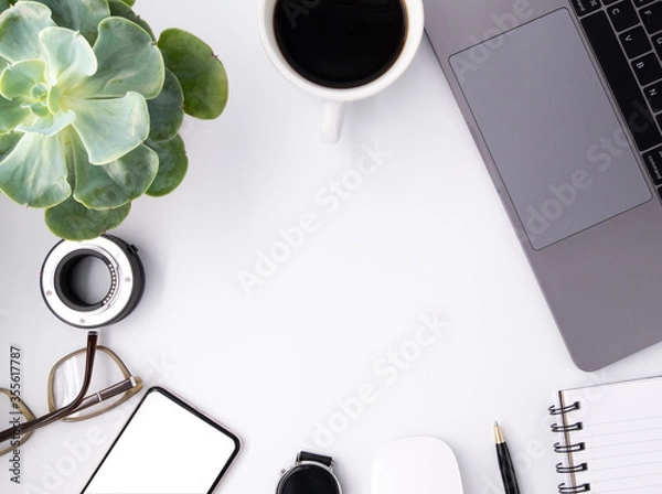 Fototapeta White office desk table with blank notebook, white blank mockup screen Tablet, laptop computer, cup of black coffee, green plant and supplies. Top view with copy space, flat lay.

