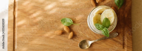 Fototapeta Vegan Chia Pudding with Banana and almond on wooden background. Vegan, morning, breakfast, healthy eating concept. Banner for website