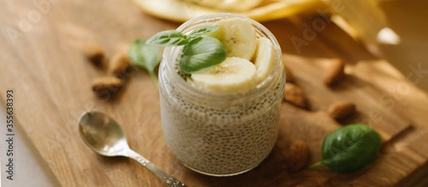 Fototapeta Vegan Chia Pudding with Banana and almond on wooden background. Vegan, morning, breakfast, healthy eating concept. Banner for website