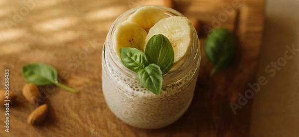 Fototapeta Vegan Chia Pudding with Banana and almond on wooden background. Vegan, morning, breakfast, healthy eating concept. Banner for website