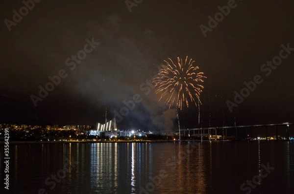 Fototapeta Beautiful firework on night sky in tromsoe city with bridge, cathedral and colorful reflection on the cold fjord water surface on new years eve