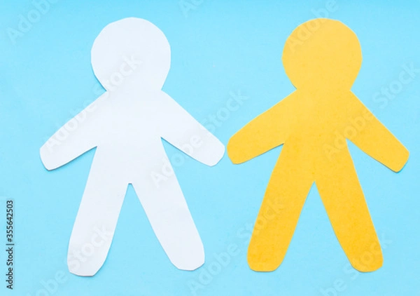 Obraz Flat lay  black, yellow, white paper people holding hands on blue background, top view. Unity concept. Stop racism, black lives matter, social exclusion message, misunderstanding, denial of society.