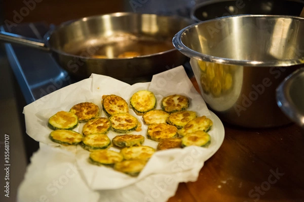 Obraz Fried zucchini rings on a tissue soaking oil. Almost ready to serve vegetarian food.