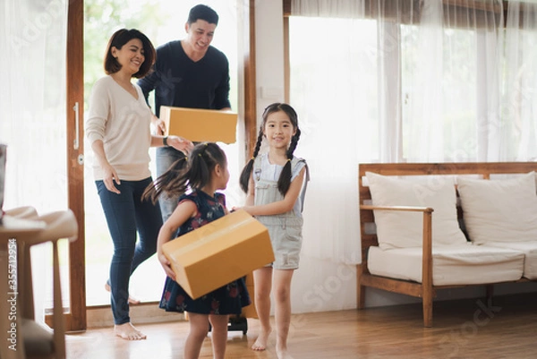 Fototapeta Young Asian family with daughter holds carton and walking in to a new home in moving relocation day which Excited smiling and felling happy. Mother Father and daughter move on a new home concept.