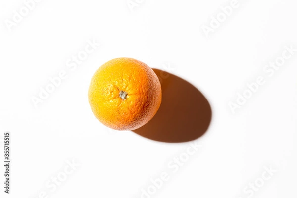 Fototapeta Fresh juicy orange on a white background with a hard shadow. Top view