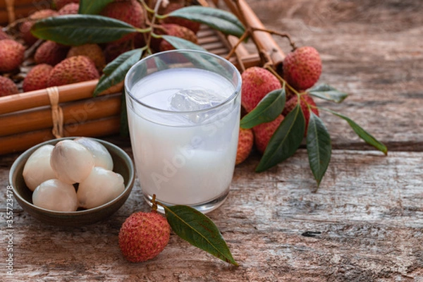 Fototapeta Sweet lychee juice on the wooden rustic background Closeup of fresh lychee juice with fruits.