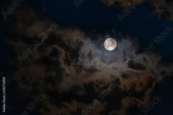 Fototapeta Full Moon peaking through beautiful cloudscape