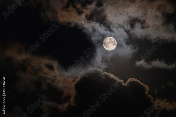 Fototapeta Full Moon peaking through beautiful cloudscape