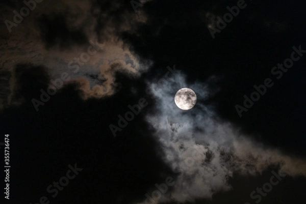 Fototapeta Full Moon peaking through beautiful cloudscape