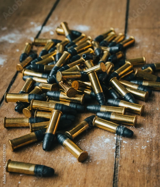 Fototapeta .22 ammunition in pile on a board surrounded by powder