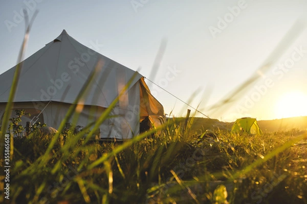 Obraz path to a glamping tent in the middle of a green field in the sunset rays. Camping and outdoor concept.