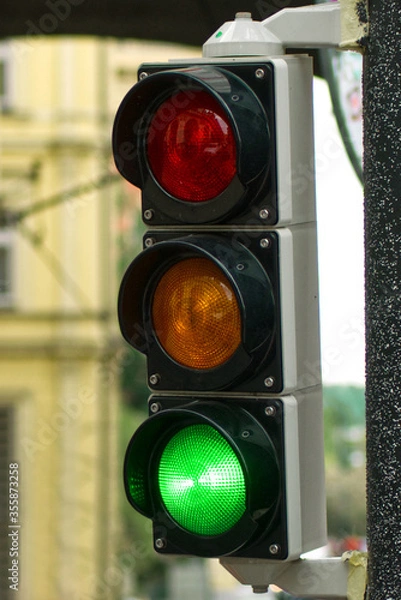 Obraz Traffic light with red, yellow and green lights showing green for start