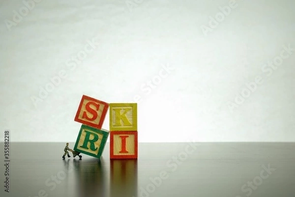 Fototapeta Isolated wooden letter block stacked to form RISK with miniature worker on job  Conceptual image of risk and uncertainty. 
