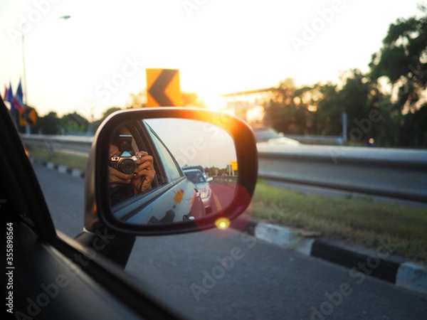 Obraz The man use camera to take the photo sunset on the car. Backlight photography.
