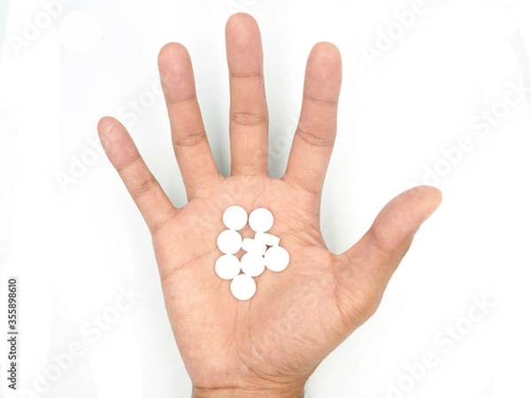 Fototapeta White pills on hand on white background with clipping path included.