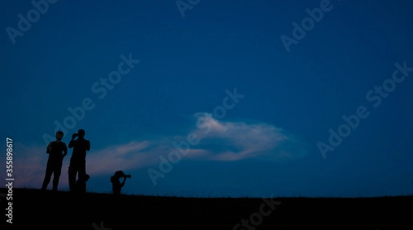 Fototapeta Silhouette crowd people stand in the dark night and see into the sky