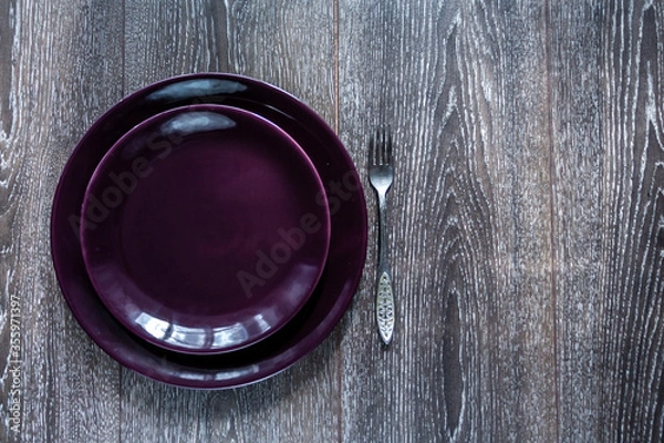 Obraz Empty purple plate and a fork on a dark wooden background. Free space for text or logo. Top view.