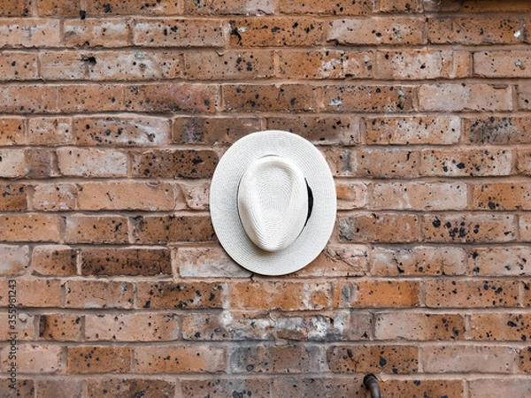 Obraz White hat with black detail on a red brick wall