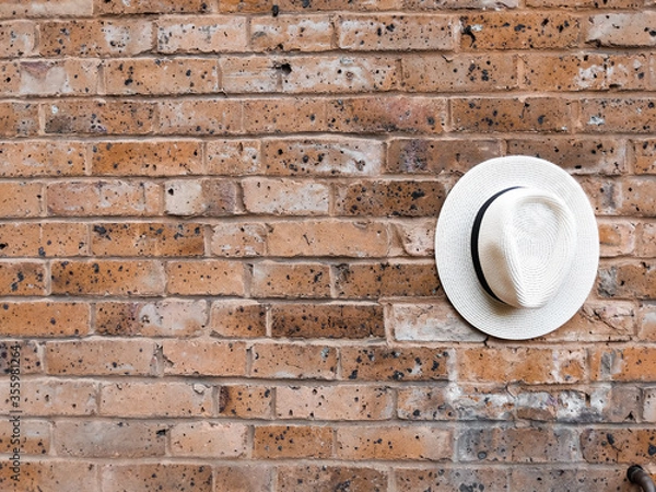 Obraz White hat with black detail on a red brick wall
