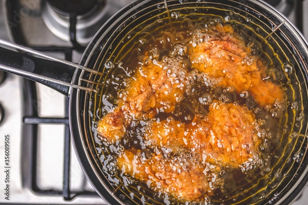 Fototapeta Frying Chicken in a pan full of oil. A pan with a frying basket. Concept of preparing Fried ORGANIC CHICKEN DRUMSTICK on the gas stove.