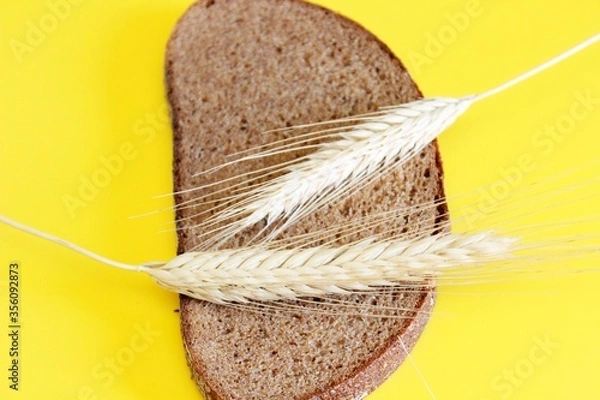 Obraz A piece of rye claid and rye ear laid on a yellow background