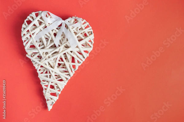 Fototapeta Wicker heart ornament on a red colored background.