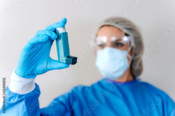Obraz Female doctor holding asthma inhaler on color background, closeup. Medical object.