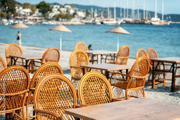 Fototapeta An empty cafe by the sea in the resort town is waiting for guests and clients, empty city spaces. Summer vacation concept