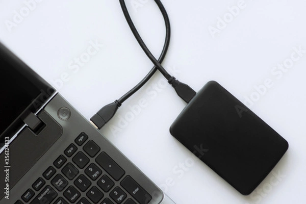 Fototapeta External backup disk hard drive connected to laptop. hard drive backup disk external computer data usb concept