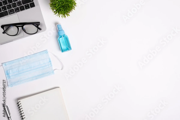 Fototapeta The equipment to protect COVID-19, blue mask and hand cleaner gel for preparing to work from home Isolated on white background concept.