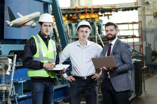 Fototapeta Portrait of a 3 men in a airplane manufactory. Two company managers and one factory worker deciding future plans. Business solution.