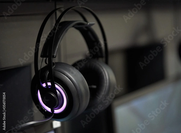Obraz Professional gaming headphones with bright side led lights hanging off the monitor.